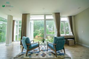 a living room with two chairs and a table and a large window at Lan Anh Villas Resort in Da Lat