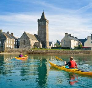 two people kayaking on the water in front of a castle at Détente à Portbail in Portbail