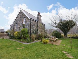 an old stone house with a picnic table in the yard at Glyn Morfa in Harlech