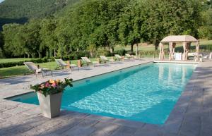a swimming pool with chairs and a gazebo at Villa Benveduti in Gubbio