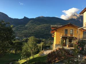 a yellow house with mountains in the background at Le jardin de Pierre in Nus