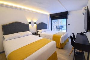 a hotel room with two beds and a desk at Hotel Tamara in Puebla