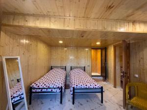 two beds in a room with wooden walls at Nato & Lado in Sighnaghi
