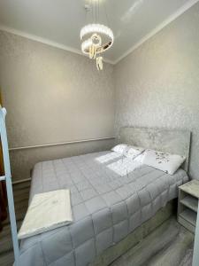 a bedroom with a bed and a chandelier at Karakol Aksuu guest house in Teploklyuchinskoye