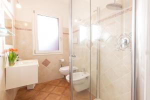 a bathroom with a toilet and a glass shower at Ventimiglia Garden Suite in Olbia