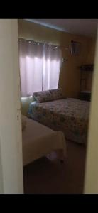 a hotel room with two beds and a window at Aconchego perto da praia in Aracaju