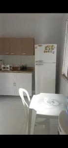 a white kitchen with a white chair and a refrigerator at Aconchego perto da praia in Aracaju