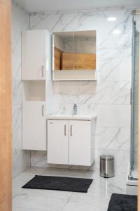 a white bathroom with a sink and a mirror at Edi Residence in Oplotnica