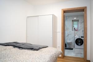 a white bedroom with a bed and a bathroom at Edi Residence in Oplotnica