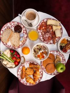 a table with many plates of food and a cup of coffee at Hôtel Saint Christophe Aix en Provence Centre Ville by Germain Collection in Aix-en-Provence