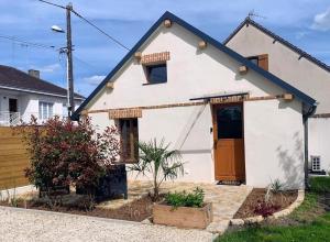 a white house with a brown door in a yard at Le Garage in Lamotte-Beuvron