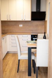 a kitchen with white cabinets and a table with a white chair at Edi Residence in Oplotnica