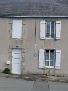 a building with two windows and a white door at Gîte La Caillère in Moncoutant