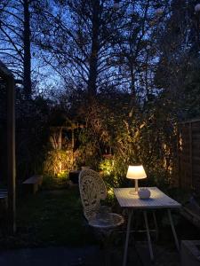 a table and two chairs with a lamp on it at Cosy hideaway with garden sauna in Cambridge in Cambridge
