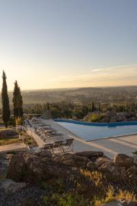 a pool with tables and chairs on top of a hill at Elegance Hotel Tandil in Tandil