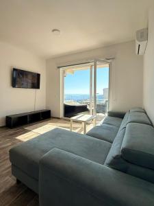 ein Wohnzimmer mit einem blauen Sofa und einem großen Fenster in der Unterkunft Manya in Seoca