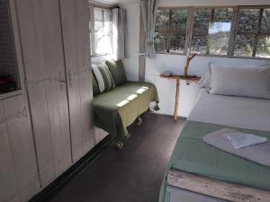 a small room with a bed and a couch and windows at Cabane sous les oliviers in Saint-Ambroix