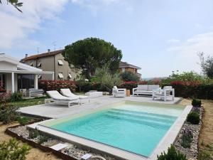 a swimming pool with lounge chairs and a house at White House in Civitanova Marche