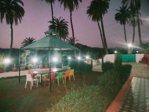 a table and chairs under an umbrella at night at Laxmanji villas in Mount Ābu