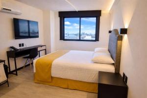 a bedroom with a bed and a desk and a window at Hotel Tamara in Puebla +46 photos