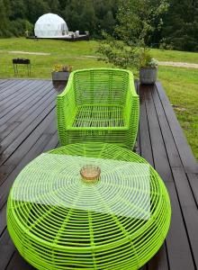 a green bench sitting on a wooden deck at Ozols in Vecpiebalga +7 photos