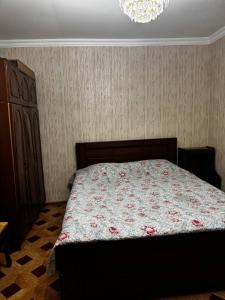 a bedroom with a bed with a floral comforter at Tskaltubo Guesthouse Oda in Tsqaltubo