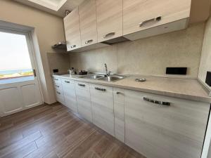 a kitchen with white cabinets and a sink and a window at La Rosa dei Venti in SantʼAntìoco