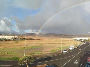 a rainbow in the sky over a road with cars at La Majorera Luminoso apartamento de 3 dormitorios en Puerto del Rosario in Puerto del Rosario