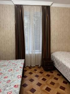 a bedroom with two beds and a window with curtains at Tskaltubo Guesthouse Oda in Tsqaltubo