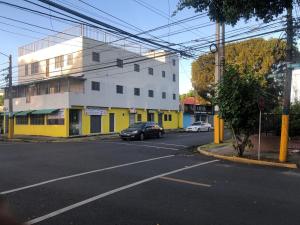 a yellow and white building with a car parked on the street at Miami Studios DR in Santo Domingo