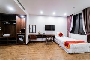 a bedroom with a bed and a desk and a tv at Khách Sạn Melanta - FLC Sầm Sơn in Sầm Sơn