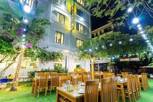 a restaurant with tables and chairs in front of a building at Khách Sạn Melanta - FLC Sầm Sơn in Sầm Sơn