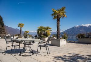 a patio with a table and chairs and palm trees at Ferienwohnung D22 in Orselina