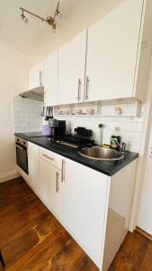 a kitchen with white cabinets and a sink at Broadway Apartment in London