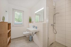 a white bathroom with a sink and a shower at Hart Backbord in Loddin +23 photos