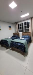 two beds sitting in a room with a window at Serra & Sossego in Araras Petropolis