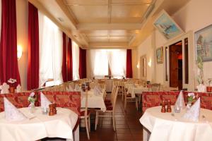a restaurant with white tables and chairs and red curtains at Budget Messehotel by Daucher in Nuremberg