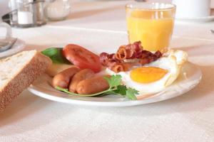 a plate of breakfast food with eggs bacon tomatoes and a glass of orange juice at Budget Messehotel by Daucher in Nuremberg