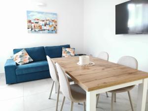 a dining room with a table and a blue couch at Domus Soli in Teulada