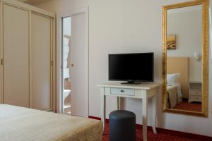 a bedroom with a television and a table with a mirror at Hotel Alexander in Riccione