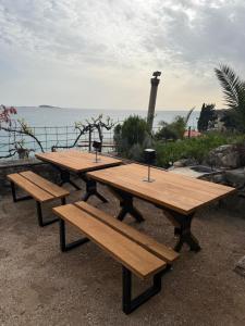 a group of picnic tables with a lighthouse in the background at Old Stone House in Mlini