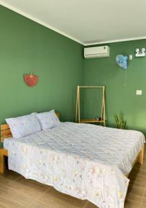 a bed in a bedroom with a green wall at Xóm Chài Homestay in Thôn Sơn Hải