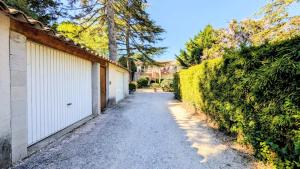 a driveway with two garages and a fence at Le jardin Provençal in Saint-Saturnin-lès-Avignon