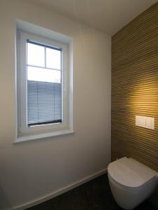 a bathroom with a toilet and a window at Ferienhaus Das Petermännchen in Fehmarn +16 photos