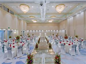 um grande salão de banquetes com mesas e cadeiras brancas em JEN Shenyang by Shangri-La em Shenyang