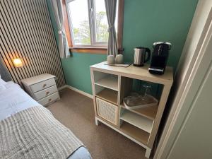 a bedroom with a table with a coffee maker on it at The Otter Lodge in Broadford