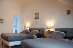 a bedroom with two beds and two lamps on the wall at Le Relais de Poste in Orbigny