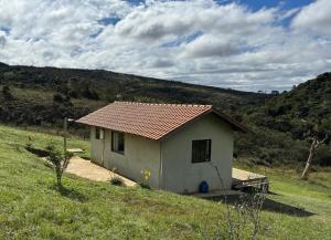 a small house in the middle of a field at Chalé Amanhecer in Aiuruoca