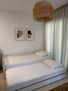 a white bedroom with two beds and a chandelier at Notos Blue in Tsoutsouros