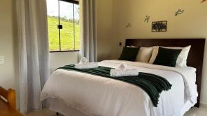 a bedroom with a large bed with two towels on it at Chalé Amanhecer in Aiuruoca